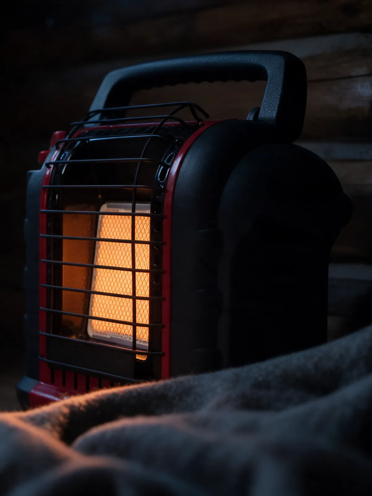Mr. Heater Portable Buddy propane heater glowing in a dark log cabin at night
